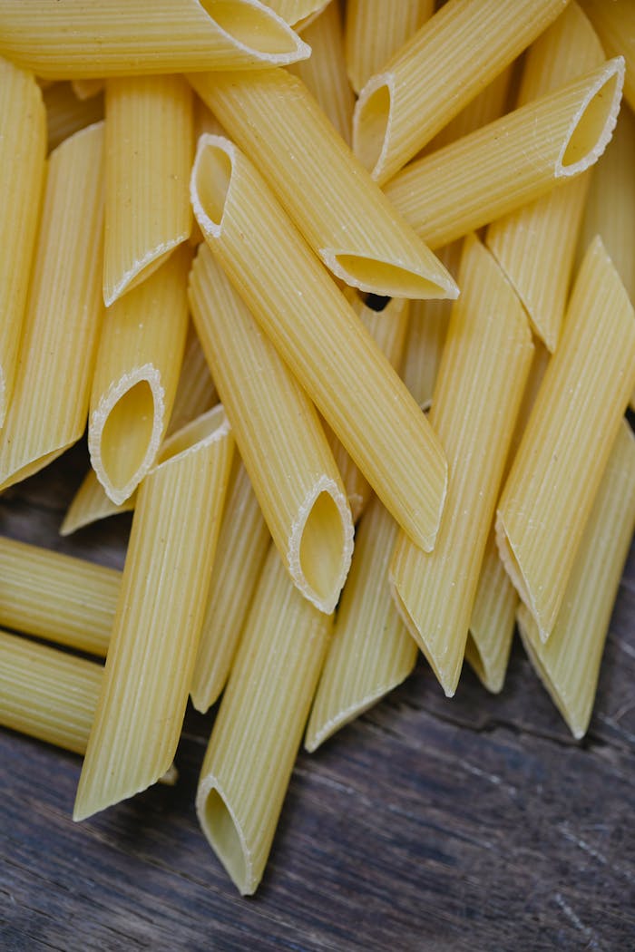 A high-resolution image of uncooked penne pasta on a wooden surface, perfect for culinary themes.